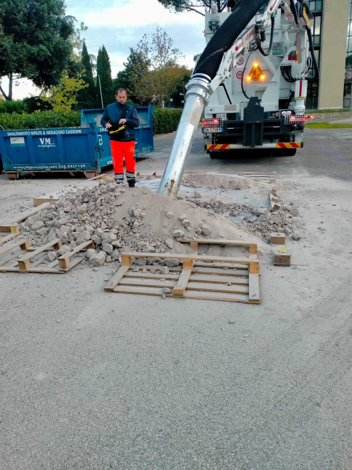 Operatore guida il tubo di aspirazione fra i detriti