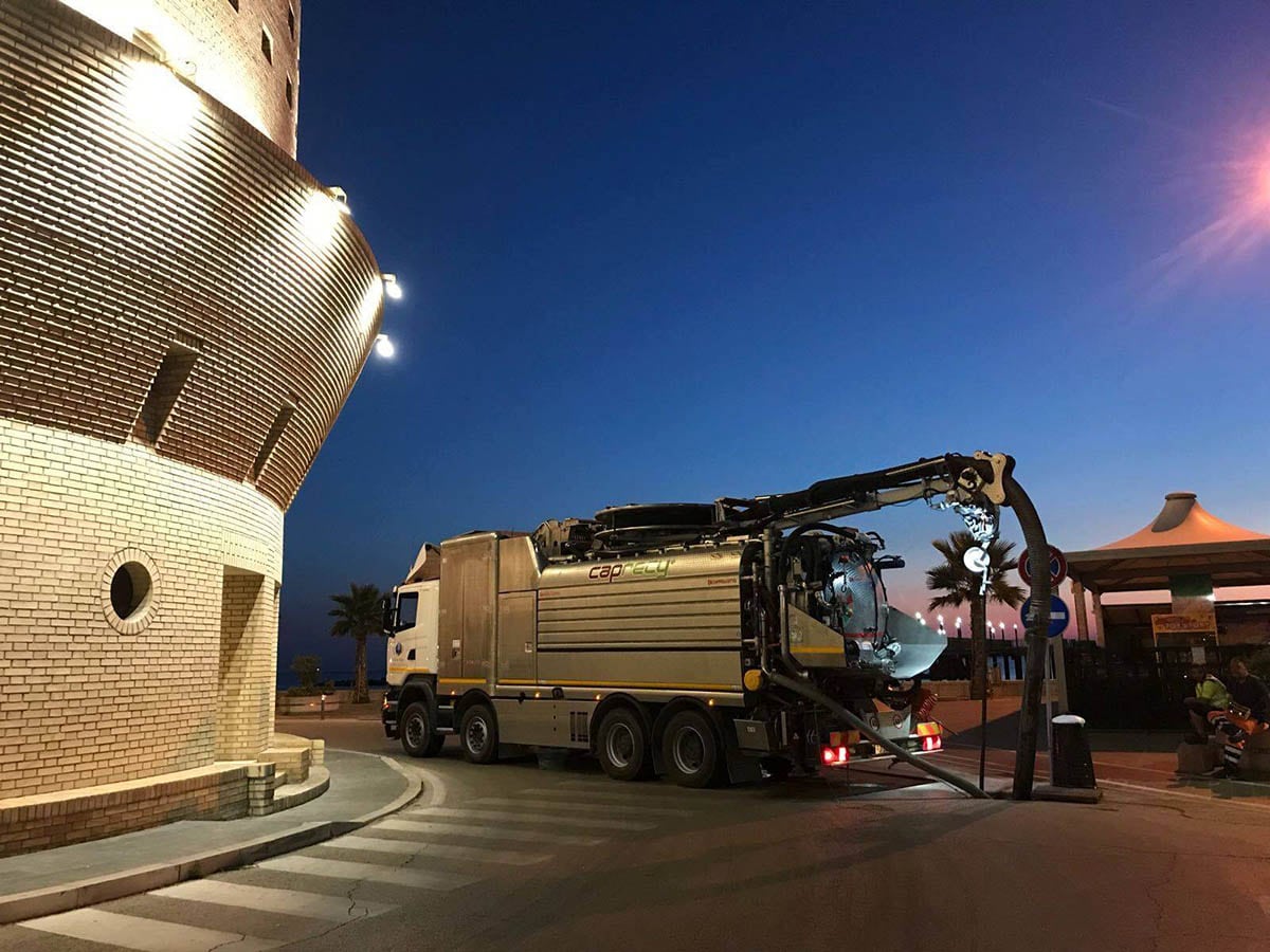 Intervento di spurgo notturno davanti a un edificio illuminato